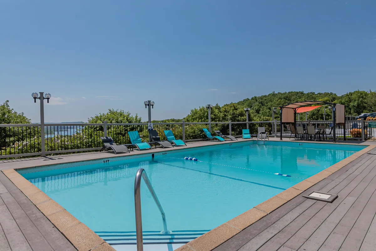 This exterior image showcases a swimming pool surrounded by lounge chairs with a landscape view beyond, evoking a sense of leisure and relaxation. The setting is ideal for sunbathing, swimming, or simply unwinding with a book by the water.