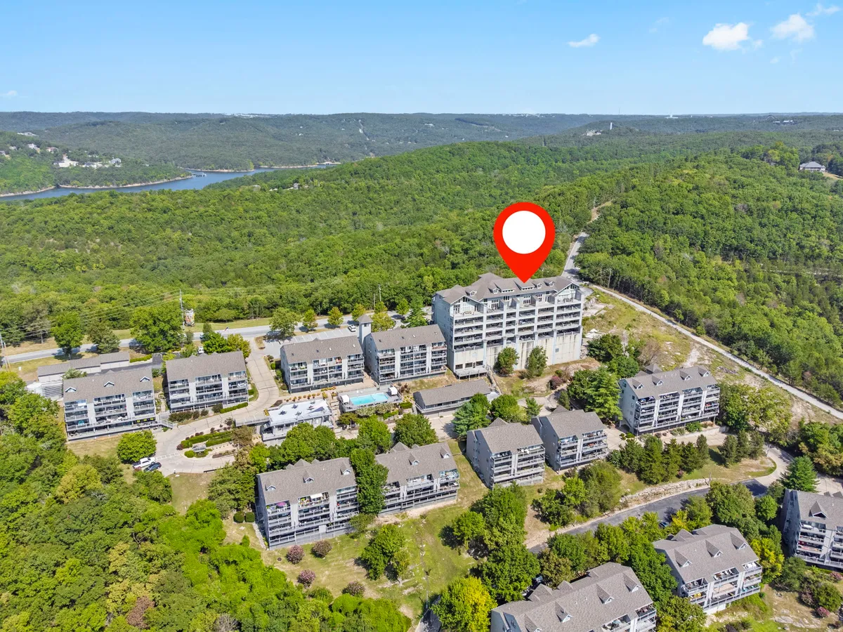 A vibrant scene featuring multi-story resort buildings nestled in lush greenery with a swimming pool in the foreground. Nature trails wind around the property, with scenic views that evoke peace and opportunity for exploration.