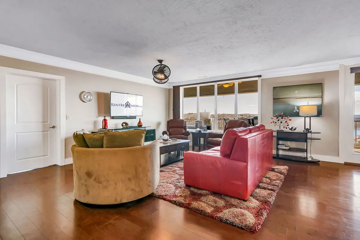An inviting interior with a red sofa, green chair, television, dining table, and large windows. The open layout and unobstructed pathways emphasize mobility and comfort, while natural light floods the space.